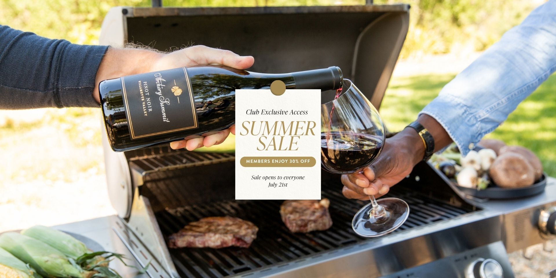 Two people pour red wine into a glass in front of a barbecue grill with steaks and vegetables. A sign advertises a summer wine sale with 50% off for members and a public sale date of July 31st.