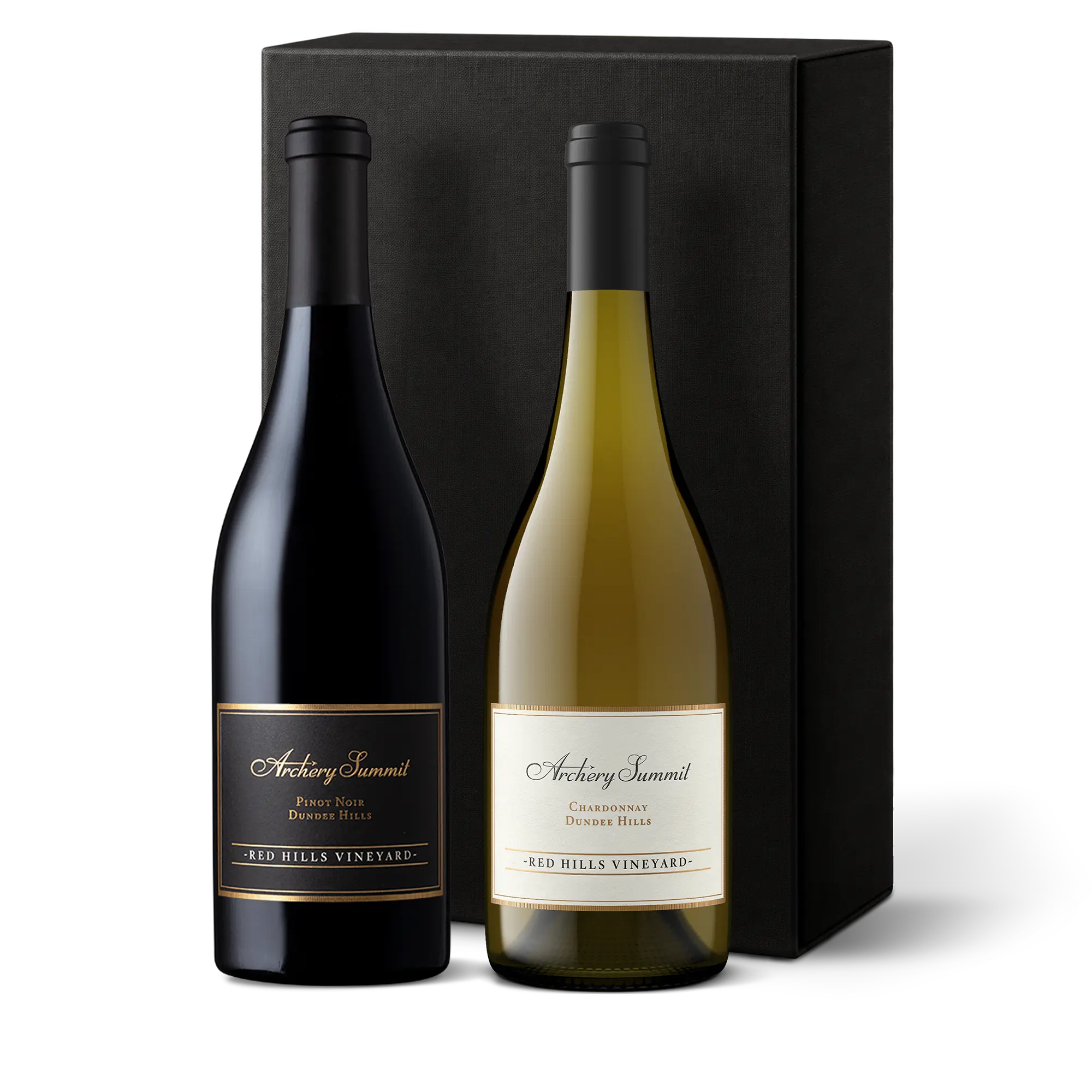 Two bottles of Archery Summit wine, a Pinot Noir and a Chardonnay, stand side by side in front of a tall black gift box. Both bottles have elegant labels indicating Red Hills Vineyard..